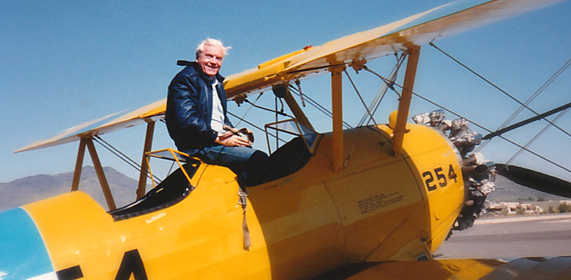 Father John seated in the cockpit of a yellow biplane